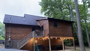 Een houten huis met twee verdiepingen, een balkon, een terras en lichtjes.