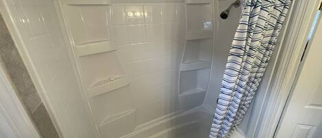 A walk-in shower with a glass door, a metal shower rod, and a striped shower curtain.
