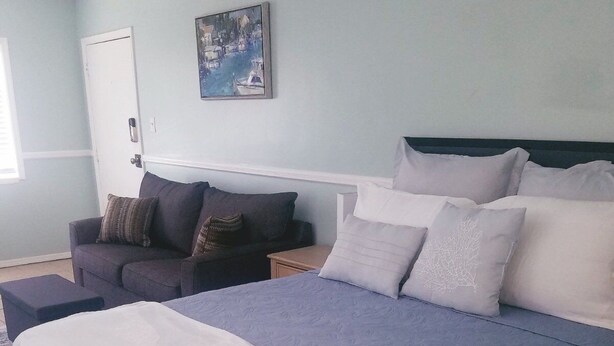 Un dormitorio con una cama grande, un sofá y un cuadro en la pared.