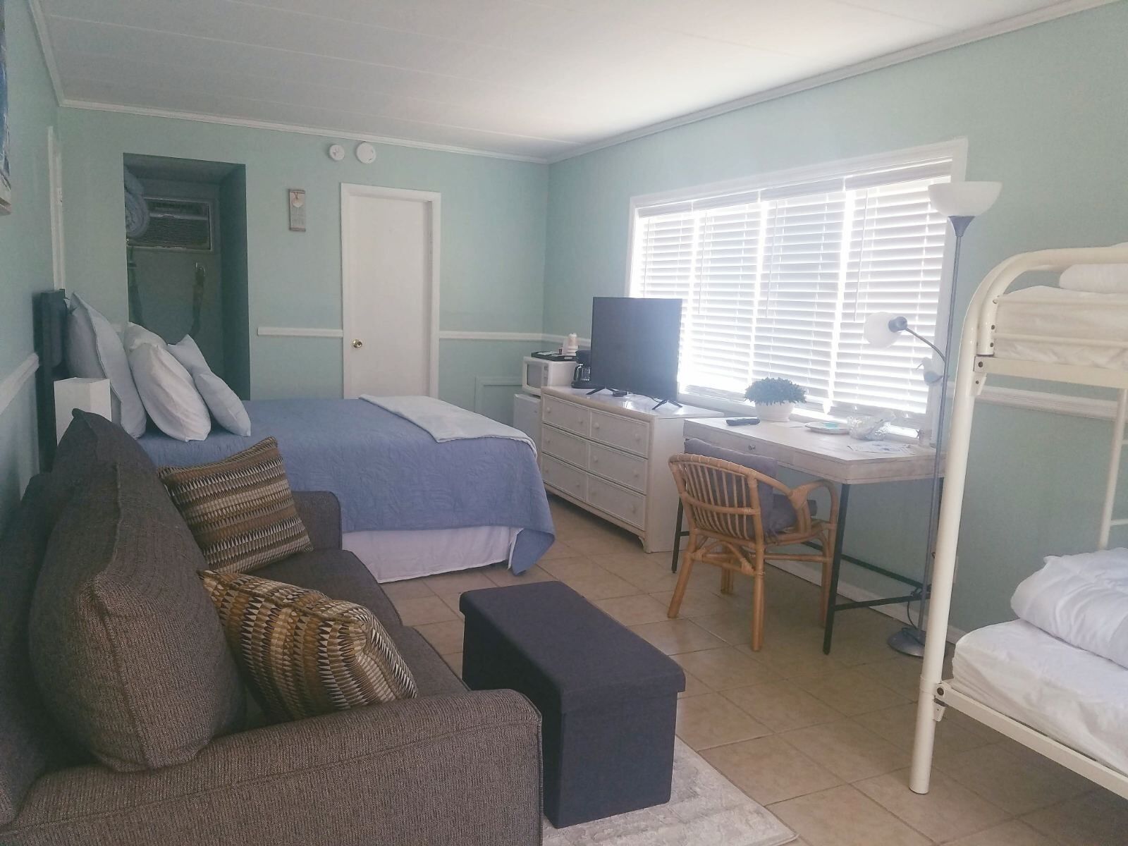 A bedroom with a bed, a desk, a chair, a TV, and a bunk bed.