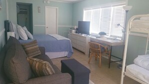 Un dormitorio con una cama, un escritorio, una silla, un televisor y una litera.