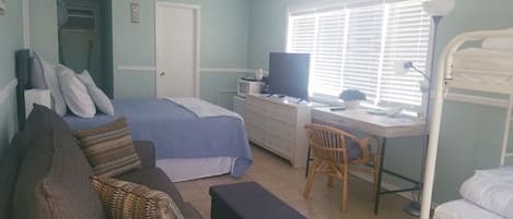 A bedroom with a bed, a desk, a chair, a TV, and a bunk bed.