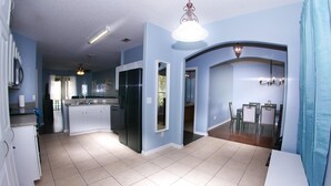 A spacious kitchen with a central island, a dining area with a chandelier, and a modern kitchen design.