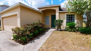 A residential house with a garage, a front door, and a driveway leading to the garage.