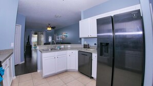 A modern kitchen with white cabinets, a stainless steel refrigerator, and a dishwasher.