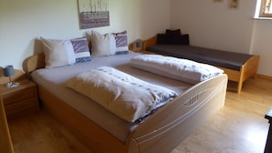 Un dormitorio con una cama grande, una mesita de noche, un banco y un cuadro colgado en la pared.