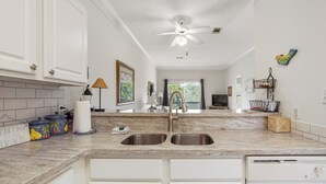 A kitchen with two sinks, a ceiling fan, and a television. - Great cozy beach getaway (Santa Rosa Beach)