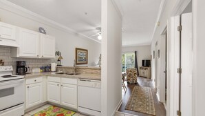 A spacious kitchen with white cabinets, a coffee maker, and a dining area with a patterned rug. - Great cozy beach getaway (Santa Rosa Beach)