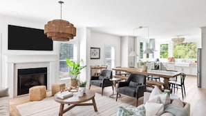 A modern living room with a fireplace, dining area, and kitchen. - Tulum-inspired coastal retreat w/ private pool, hot tub & yoga porch (Folly Beach)