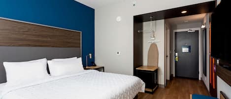 Una habitación de hotel moderna con una cama grande, una mesita de noche, un escritorio y un televisor.