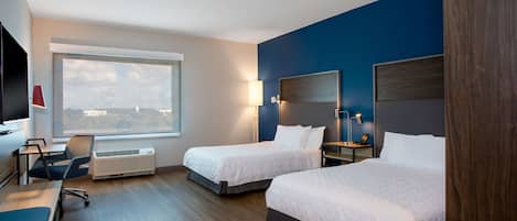Une chambre d’hôtel avec deux lits, un bureau, une chaise, une télévision et une fenêtre donnant sur un beau paysage.