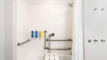 Une salle de bain moderne avec une baignoire blanche, des barres d’appui et une pomme de douche.