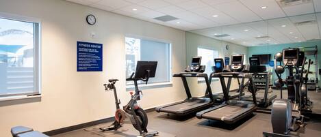 Un gimnasio con cintas de correr, elíptica y bicicleta estática.