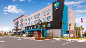 Un hotel moderno con un llamativo logo 'tu', fachada azul y gris, y palmeras en el paisajismo.
