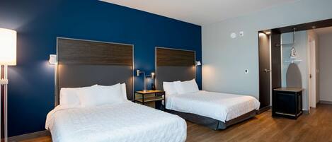 Una habitación de hotel con dos camas, una mesita de noche, una lámpara y un armario.