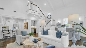 Un vaste espace de vie comprenant un escalier, des meubles blancs et un coin repas.