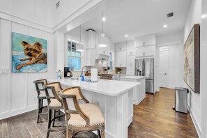 A modern kitchen with white cabinetry, a central island, and bar stools.
