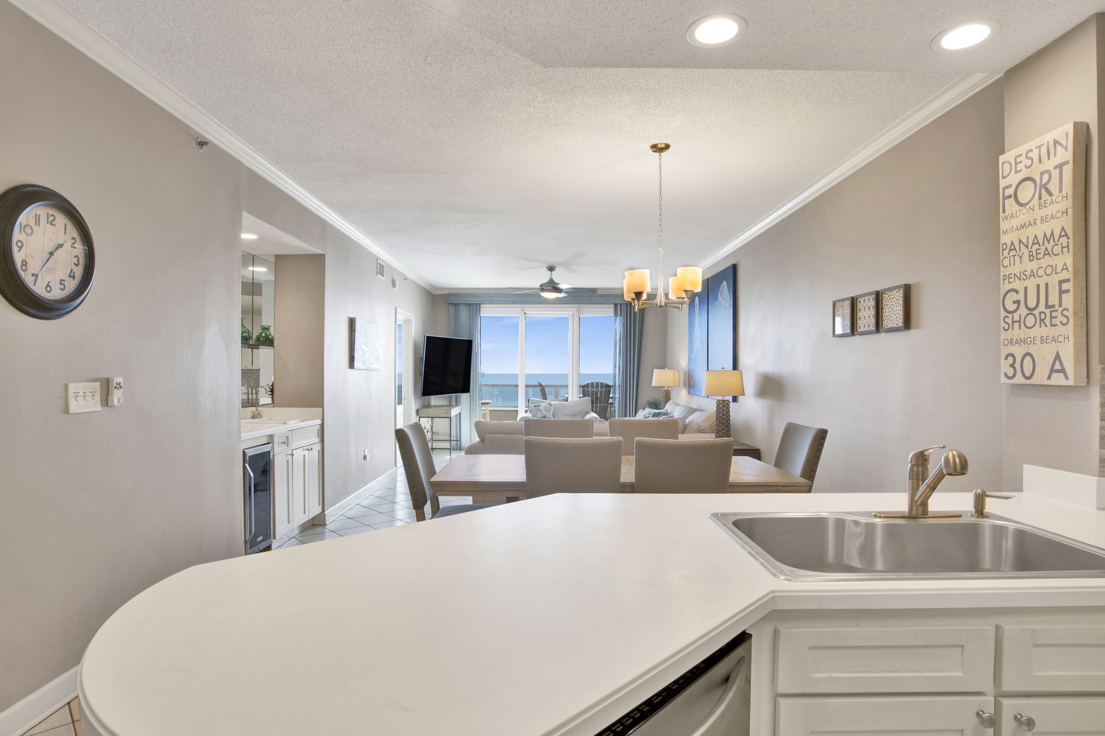 A modern kitchen with a central island, a dining area with a view, and a living space with a ceiling fan.