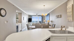 A modern kitchen with a central island, a dining area with a view, and a living space with a ceiling fan.