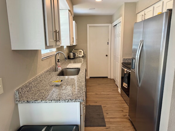 A compact kitchen with granite countertops, stainless steel appliances, and a small sink. - Cute Vacation home In the heart of Venice (Venice)