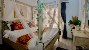 Un dormitorio con una cama, una mesita de noche, un espejo y una ventana con cortinas.