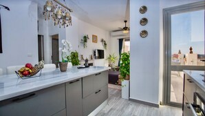 A modern kitchen with a marble countertop, built-in cabinets, and a hanging light fixture. - Chic Penthouse Retreat Elgouna Access (Hurghada)