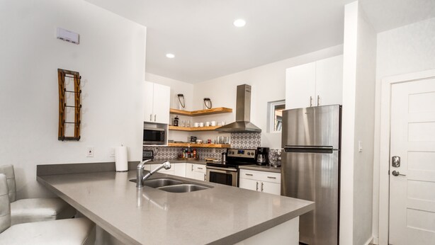 A modern kitchen with a central island, stainless steel appliances, and white cabinetry.