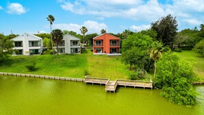 A residential area with three houses, a wooden dock, and a body of water.