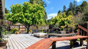 A wooden deck with outdoor furniture, including a sofa and chairs, surrounded by trees and a wooden fence. - Coastal Refuge, *Hot Tub,* Close to Town. (Trinidad)