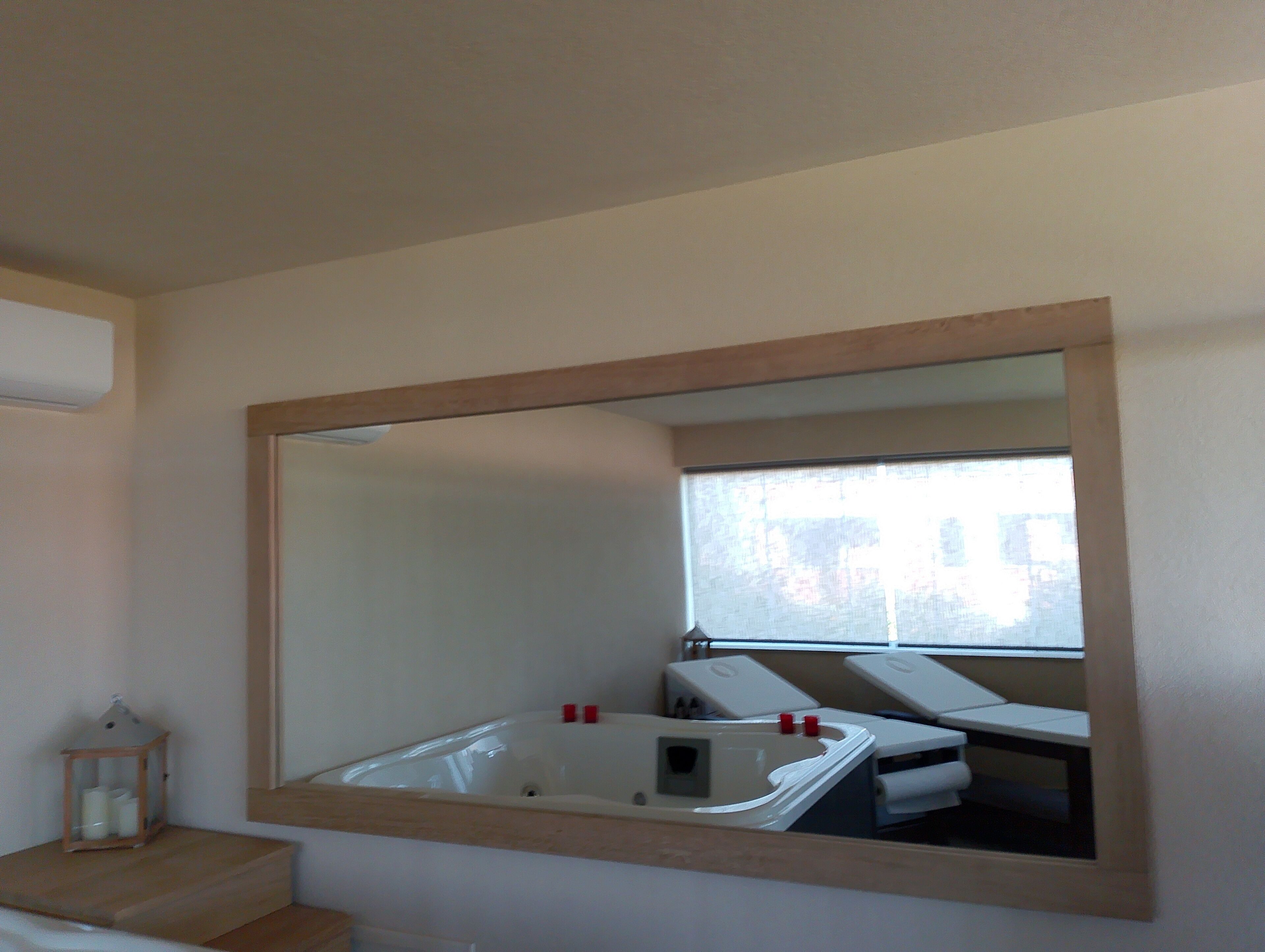 A bathroom with a large mirror, a bathtub, and a window.