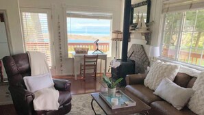 A cozy living room with a leather armchair, a brown sofa, and a coffee table with a plant and candles. A fireplace is visible in the background. - Shore Acres Ocean View Cabin and Retreat Space (McKinleyville)