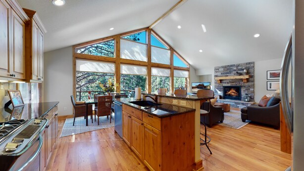 A spacious kitchen with wooden cabinets, a large island, and a dining area with chairs. - River Front/.5 mi to EP/ AC/fishing (Estes Park)