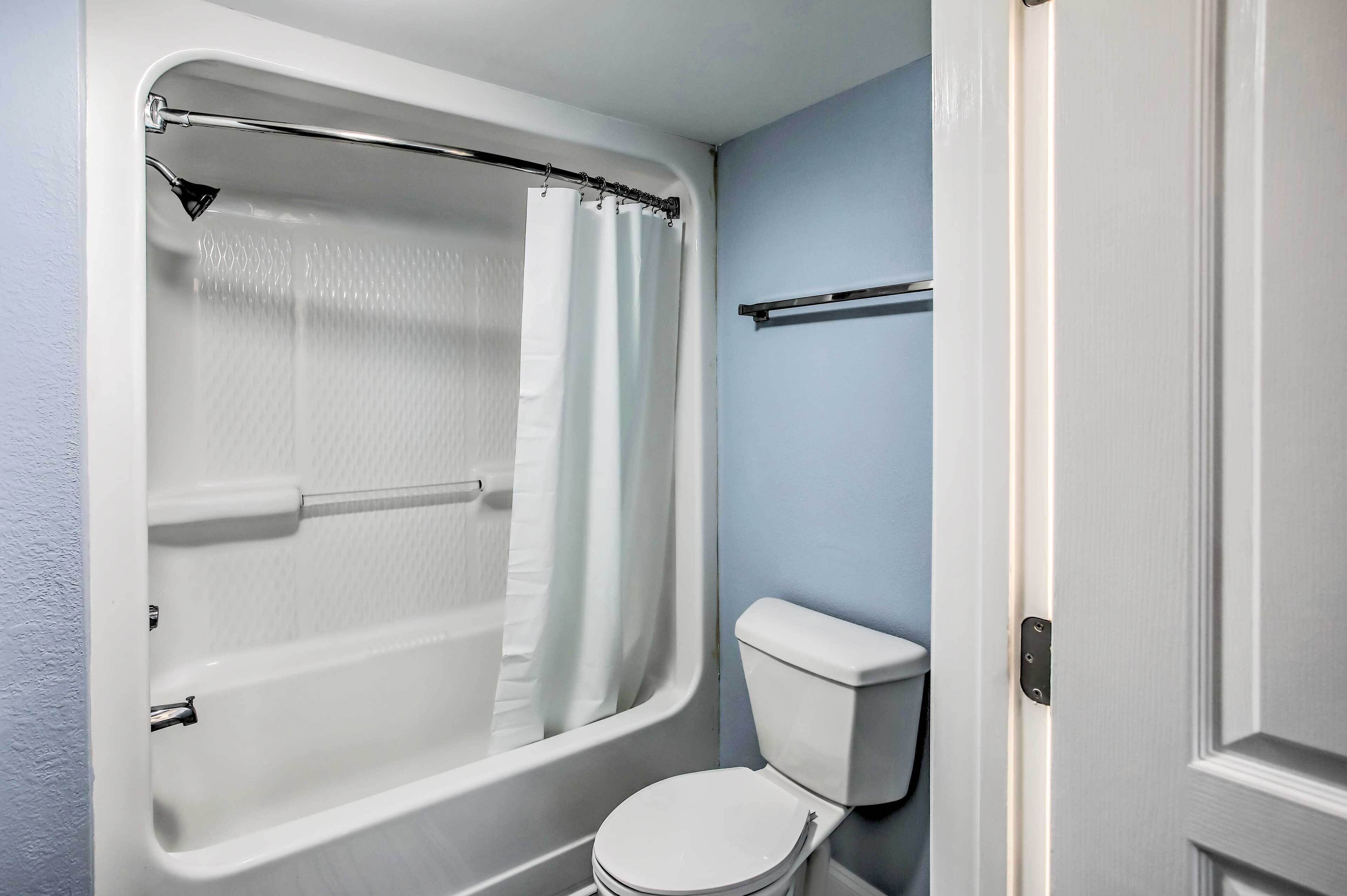 A bathroom with a bathtub, shower curtain, and toilet.