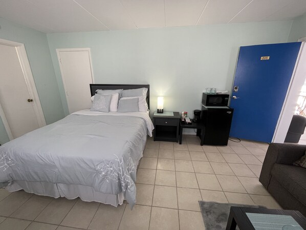A bedroom with a bed, bedside tables, a nightstand, a microwave, a blue door, and a grey sofa. - LOCATION!Getaway,cozy place block from everything!Free ice cream,espresso drinks (Wildwood)