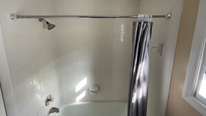 A shower area with a glass door, a towel rack, and a hand dryer.