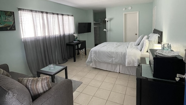 A hotel room with a bed, a sofa, a desk, and a TV.