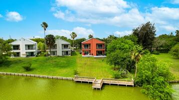 A residential area with three houses, a wooden dock, and a body of water.