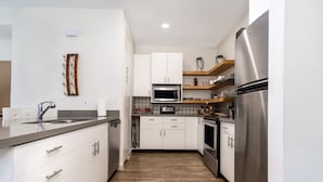Una cocina moderna con armarios blancos, un refrigerador de acero inoxidable y un microondas.
