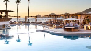 A poolside area with lounge chairs and umbrellas, surrounded by palm trees and a clear sky. - Father’s Day at ME Cabo Oceanfront on Medano Beach June 18-25th 2022 (Cabo San Lucas)