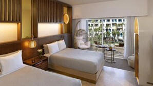 A hotel room with two beds, a hanging chair, a small table, and a view of the outdoor area. - Father’s Day at ME Cabo Oceanfront on Medano Beach June 18-25th 2022 (Cabo San Lucas)