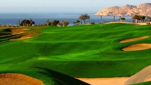 A golf course with a clear view of the ocean and mountains in the background. - Father’s Day at ME Cabo Oceanfront on Medano Beach June 18-25th 2022 (Cabo San Lucas)