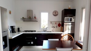 A modern kitchen with a central island, a dining table with chairs, and a window providing natural light.