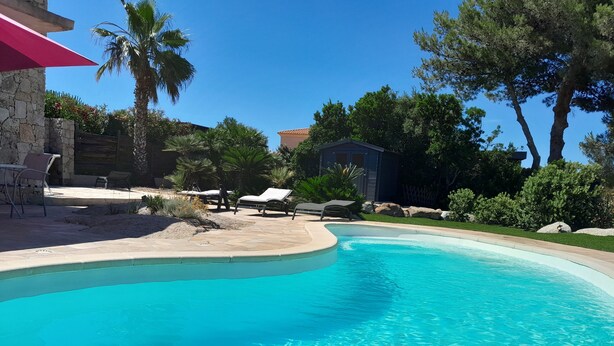 A swimming pool with lounge chairs and a stone patio.