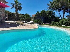 Une piscine avec des chaises longues et une terrasse en pierre.