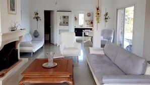 A modern living room with a fireplace, a sofa, a coffee table, and a dining area in the background.