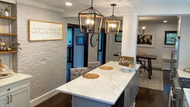 A modern kitchen with a marble island, pendant lights, and a 'Cheers' sign. - Gorgeous, Fully Remodeled Open Floor-Plan! (Pontiac)