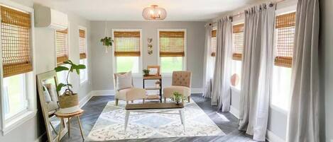 Un salon avec un parquet en chevrons, deux fauteuils, une table basse et un lustre.