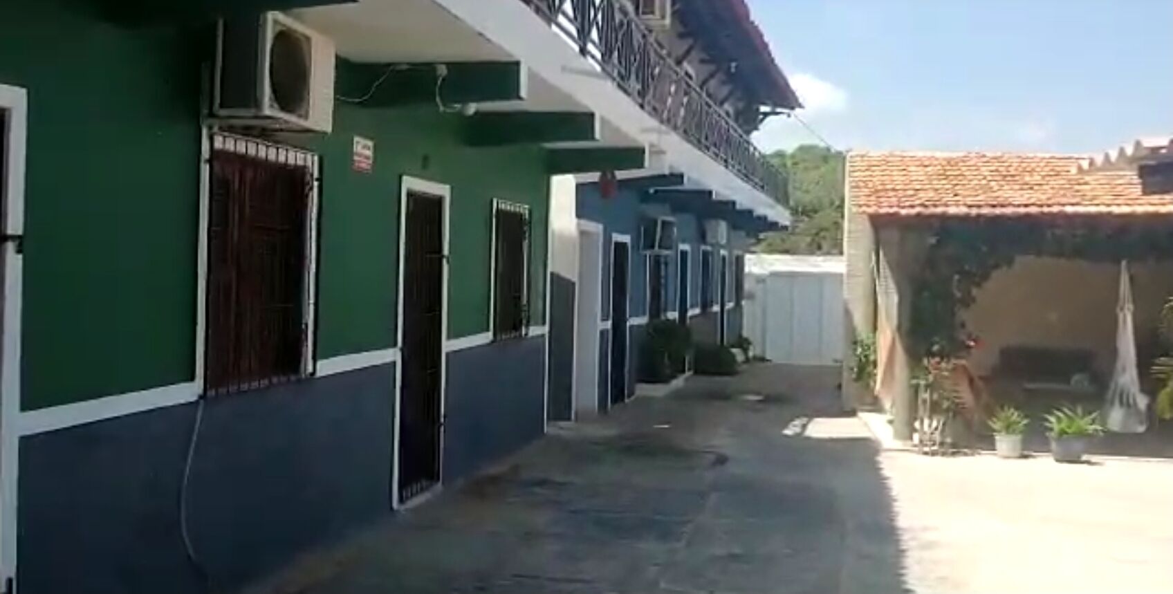 A building with a green and white facade, multiple doors, and a balcony.