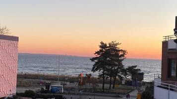 Blick auf die Küste, ein Sonnenuntergang, ein Parkplatz und ein Gebäude mit strukturierter Fassade.