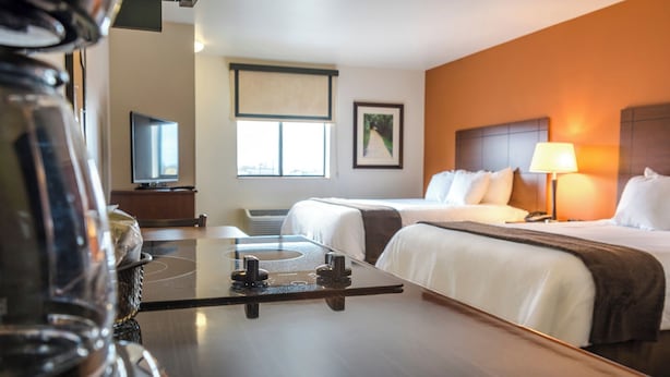 Ett hotellrum med två sängar, ett skrivbord, en tv och ett fönster med utsikt.